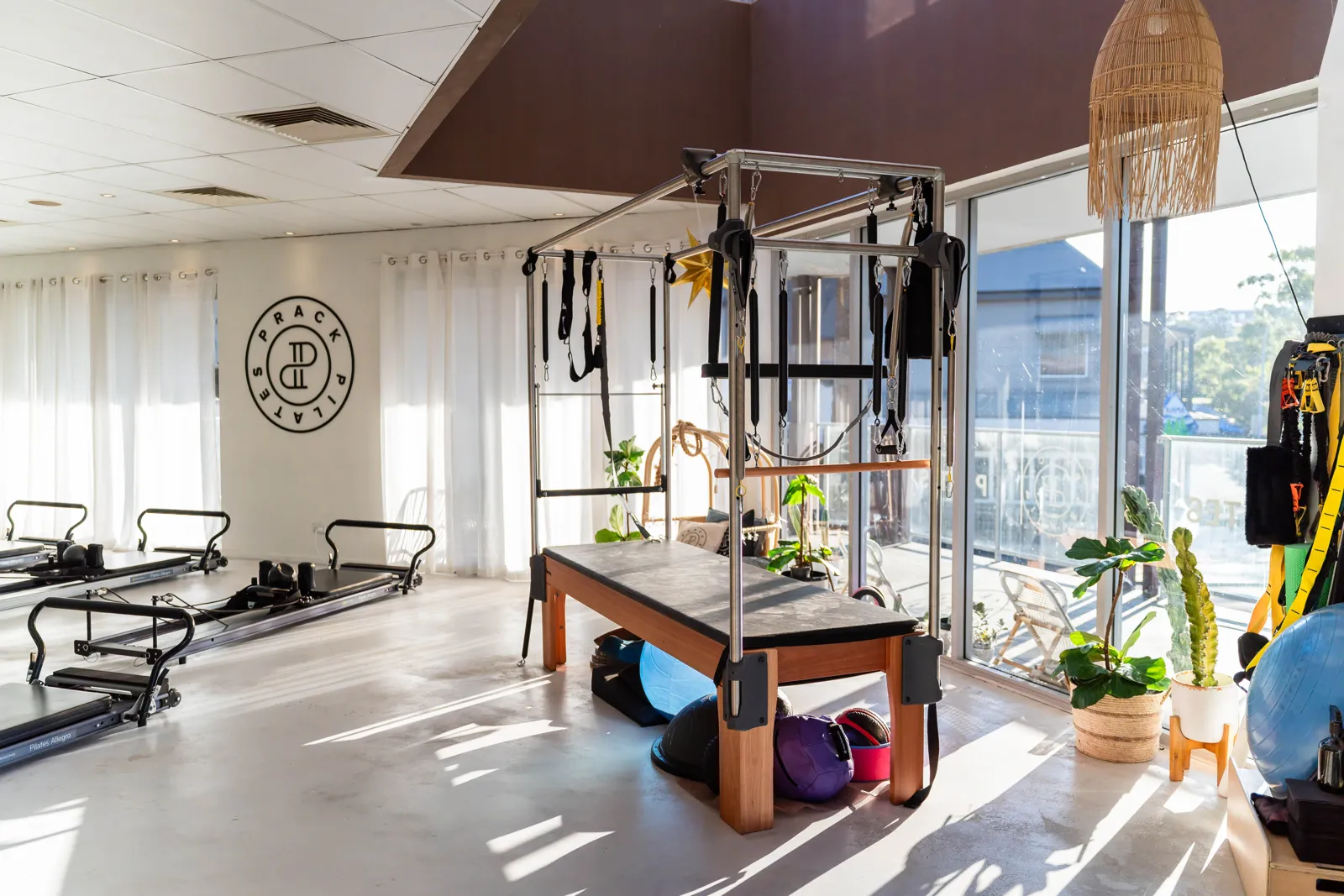 The Cadillac trapeze table in the sunlit Prack Pilates studio, with reformers lined up along the far wall
