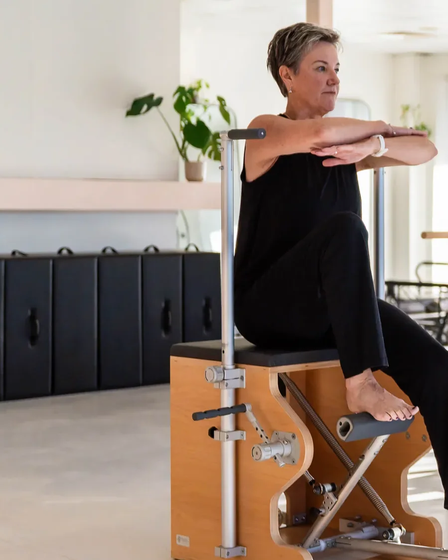 A client seated on the Wunda Chair, pressing the pedal with one foot and resting both arms across the handle
